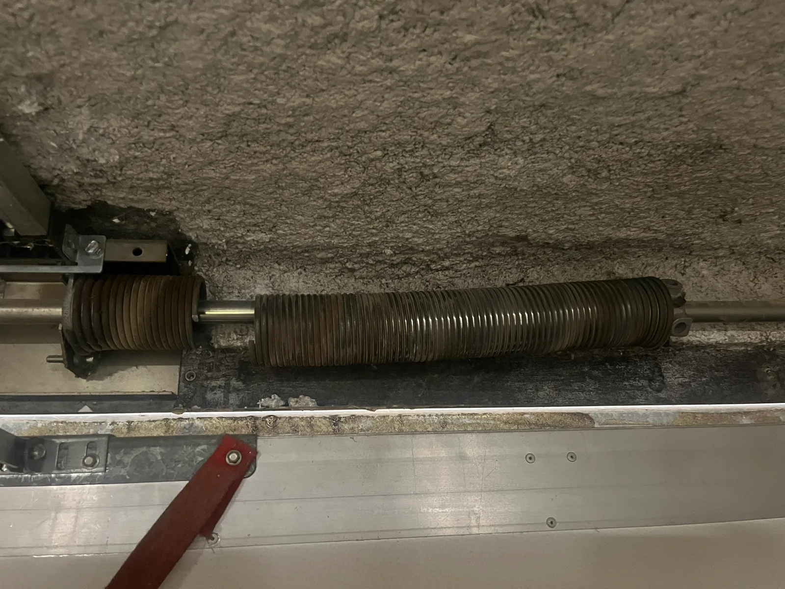 Ressort de torsion cassé en deux sur l’axe, au-dessus de la porte